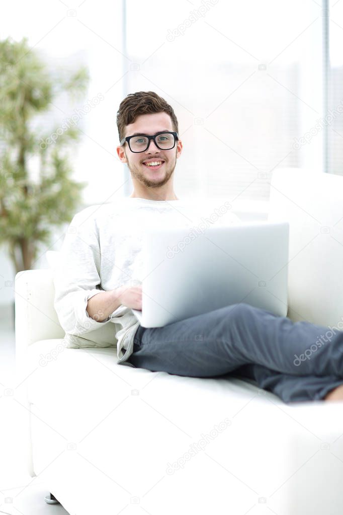 Young man using his laptop in bright living room.