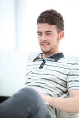 Diz üstü parlak oturma odasında kullanan mutlu genç adam.