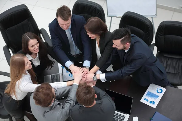 Equipo de negocios con las manos juntas en el escritorio — Foto de Stock