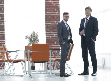 İki iş adamları modern bir ofiste duruyorsun