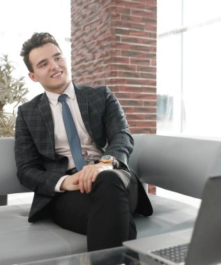 Genç işadamı ofiste dizüstü bilgisayarla çalışıyor.