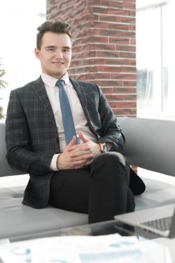 Genç işadamı ofiste dizüstü bilgisayarla çalışıyor.