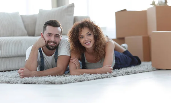 Casal feliz jaz no chão em um novo apartamento — Fotografia de Stock