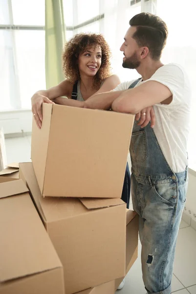 Щаслива пара, що стоїть біля коробок у своїй новій квартирі . — стокове фото