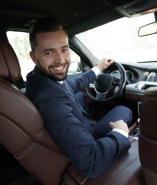 Başarılı bir adam prestijli bir arabanın direksiyonunda oturuyor.