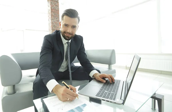 Stijlvolle man die op laptop werkt en het maken van aantekeningen in notitieblok — Stockfoto