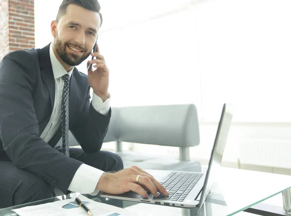 Affärsman talar på smartphone och skriva text på laptop — Stockfoto