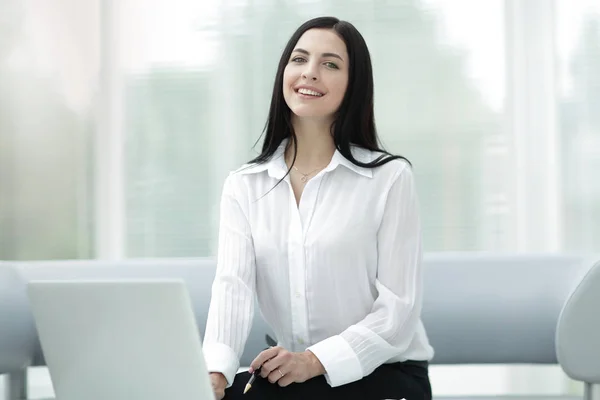 Succès jeune femme assise à un bureau sur un fond flou . — Photo