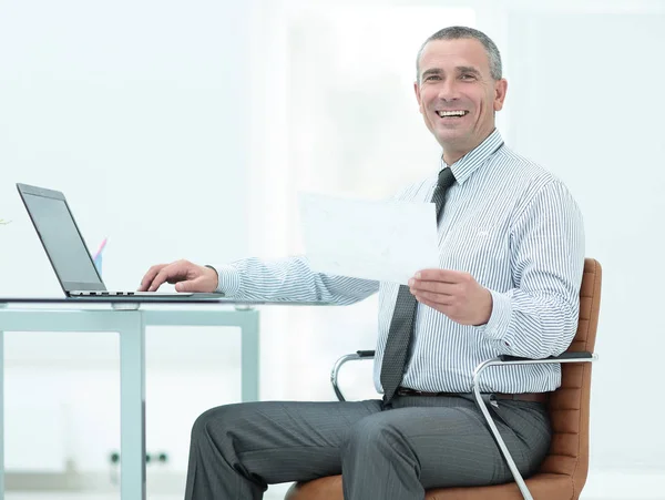 Портрет счастливого взрослого бизнесмена, сидящего за столом офиса — стоковое фото