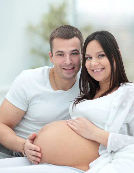 Gravid kvinna med maken avkopplande hemma — Stockfoto