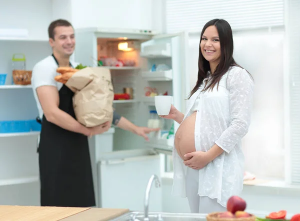 Beautiful pregnant woman with her husband in the kitchen — Stock Photo, Image