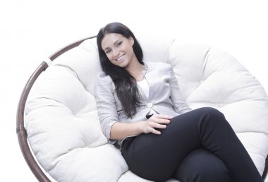 Yuvarlak, yumuşak bir sandalyede oturan modern genç kadın.