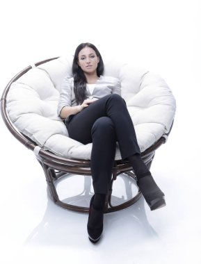Yuvarlak, yumuşak bir sandalyede oturan modern genç kadın.