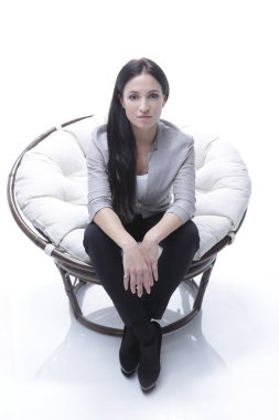 Yuvarlak, yumuşak bir sandalyede oturan modern genç kadın.