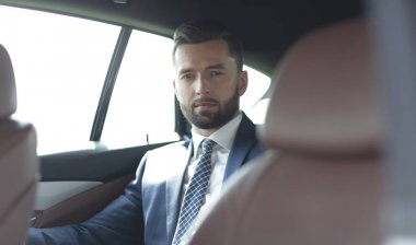 arabanın arka koltuğunda oturan yakışıklı sakallı işadamı