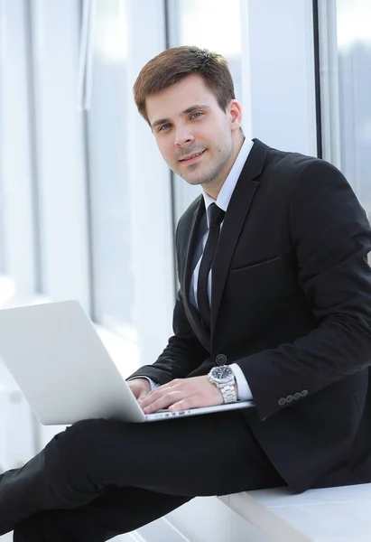 Jeune professionnel avec ordinateur portable sur fond de fenêtre de bureau — Photo