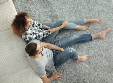 yeni bir oturma odasında bir halı üzerinde oturan yeni evli çift