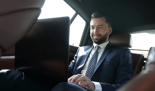 Podnikatel, pracuje na jeho laptopu, zatímco sedí v autě — Stock fotografie