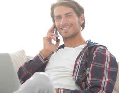 cep telefonu üzerinde konuşurken laptop ile ciddi genç adam