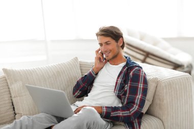 cep telefonu üzerinde konuşurken laptop ile ciddi genç adam