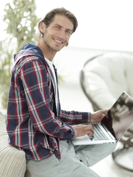 Стильний молодий чоловік працює на ноутбуці і дивиться на камеру — стокове фото