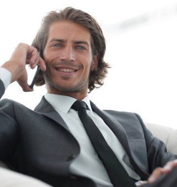 iş adamı rahat bir sandalyede otururken Smartphone'da konuşuyor.