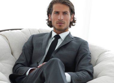 Kendine güvenen işadamı büyük bir rahat sandalyede oturuyor.