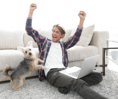 mutlu genç adam köpeğiyle oturma odasında exults