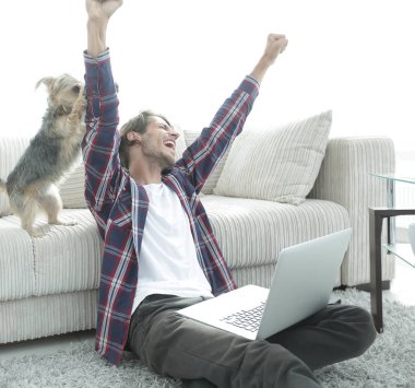 sevindirici ve yakın oturma odasında kanepede oturan ellerini yükselterek mutlu adam.