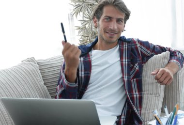 genç adam bir sehpa yakınındaki bir kanepede oturan bir dizüstü bilgisayar ile