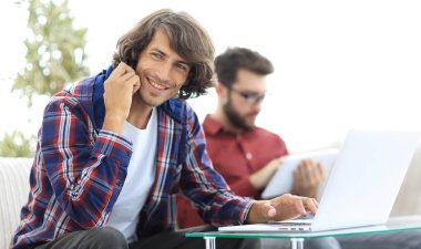 adam kanepede oturan, belgili tanımlık smartphone üzerinde konuşmak ve internette bilgi arayan bir arkadaşıyla.