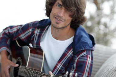 modern adam kanepede oturan gitar çalmak. bir yaşam tarzı kavramı