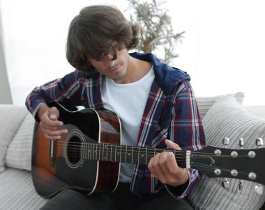 modern adam kanepede oturan gitar çalmak. bir yaşam tarzı kavramı