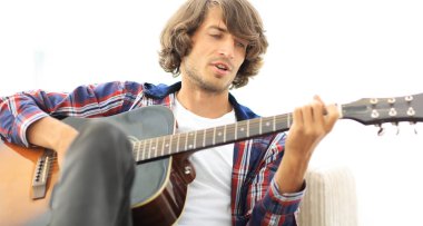 Yakışıklı adam evde kanepede gitar çalmaya