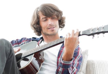 Yakışıklı adam evde kanepede gitar çalmaya
