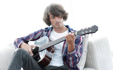Yakışıklı adam evde kanepede gitar çalmaya