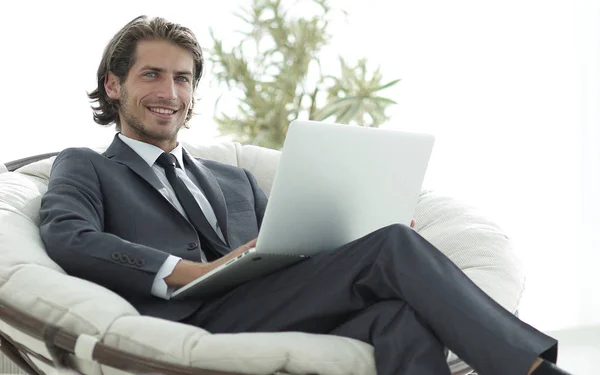 Úspěšný podnikatel s notebookem sedět v velké pohodlné armchai — Stock fotografie