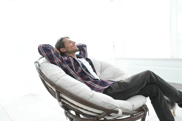 Der moderne Typ ruht sich in einem großen bequemen Stuhl aus. Seitenansicht. — Stockfoto