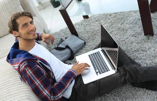 Geschäftsmann mit Laptop sitzt auf Teppich im Wohnzimmer. — Stockfoto