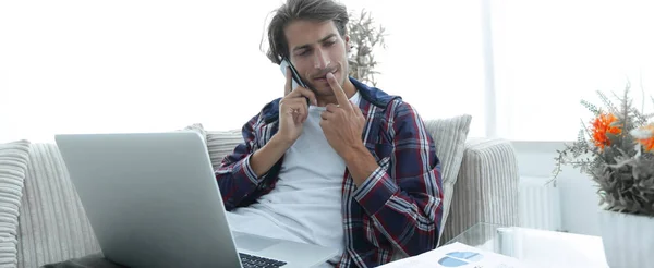 Молодой человек работает с ноутбуком обсуждая финансовые документы на дому . — стоковое фото