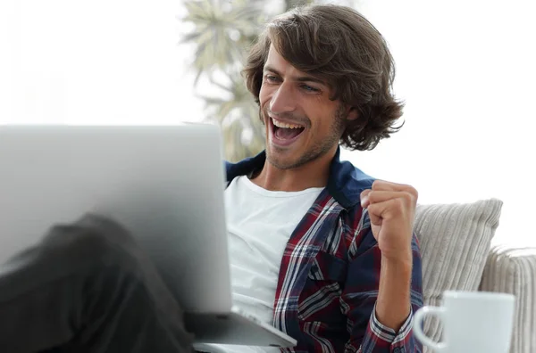 Bardzo szczęśliwy facet siedzi w pobliżu stolik do laptopa. — Zdjęcie stockowe