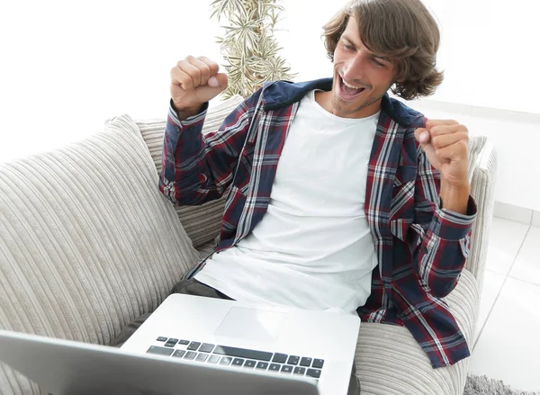 Šťastný mladý muž dívá na obrazovce přenosného počítače — Stock fotografie