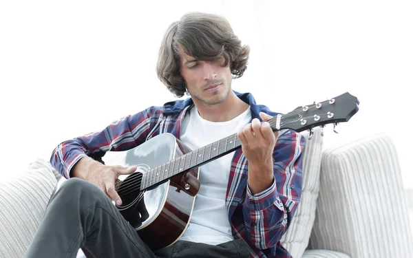 Yakışıklı adam evde kanepede gitar çalmaya