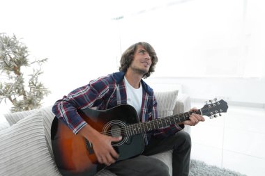 modern adam kanepede oturan gitar çalmak. bir yaşam tarzı kavramı