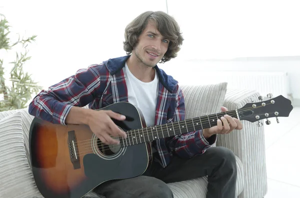 Yakışıklı adam evde kanepede gitar çalmaya