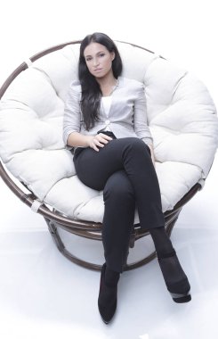 Yuvarlak, yumuşak bir sandalyede oturan modern genç kadın.