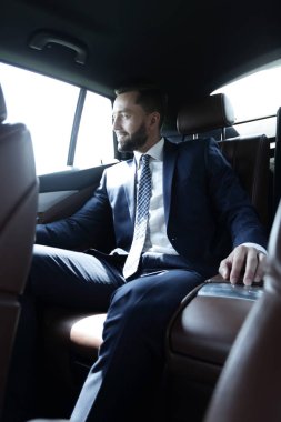 bir arabanın arka koltuğunda oturan işadamı