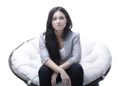 Genç kadın bir yuvarlak rahat yumuşak büyük sandalyede oturuyor.