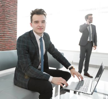 Genç işadamı ofiste dizüstü bilgisayarla çalışıyor.