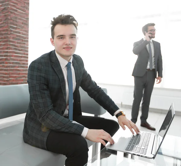 Genç işadamı ofiste dizüstü bilgisayarla çalışıyor.